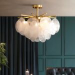 Gilded bedroom chandelier with blown glass pendants in a living room, hanging from the ceiling and lit.