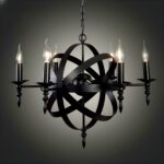Black metal chandelier resembling an atom in the center. Around this structure are fixed 6 black candlesticks with their bulbs lit. The whole is set against a black background with a white gradient in the center.