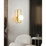 in sun salon with a white armchair, we see a modern gold wall light with a ball