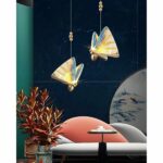 in a living room with a dark green wall, two multicolored butterfly-shaped pendant lights are shown