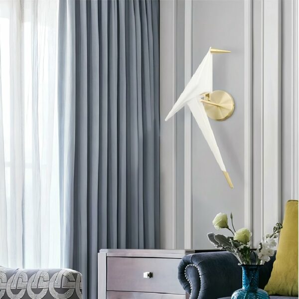 an origami wall light in the shape of a white and gold bird is featured in a gray-toned living room