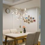 Original modern gold tree-shaped LED pendant chandelier suspended and lit above a dining table.