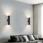 in a grey-toned living room, above a grey sofa, two black wall lights shine up and down