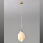 White magnolia-shaped ceramic flower hanging from the ceiling, lit on a gray background.