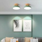 Wood and metal round ceiling fixture for the bedroom, installed on the ceiling and lit, in the green version, above a sofa.
