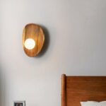Wooden wall sconce in shell style with small pearl light for hanging on a bedroom wall next to the bed.